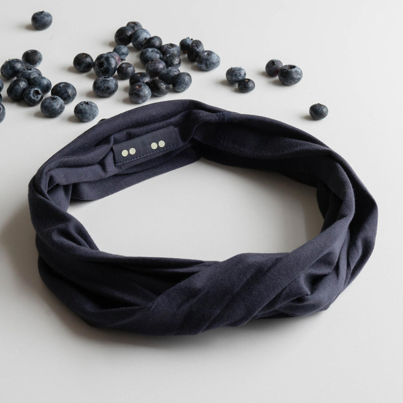 KOOSHOO organic twist headband midnight blue. Flat lay with fresh blueberries scattered around the headband off-packaging #color_midnight-blue