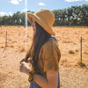 Girl standing in dry field with warm woven hat with gold sand scrunchie on wrist