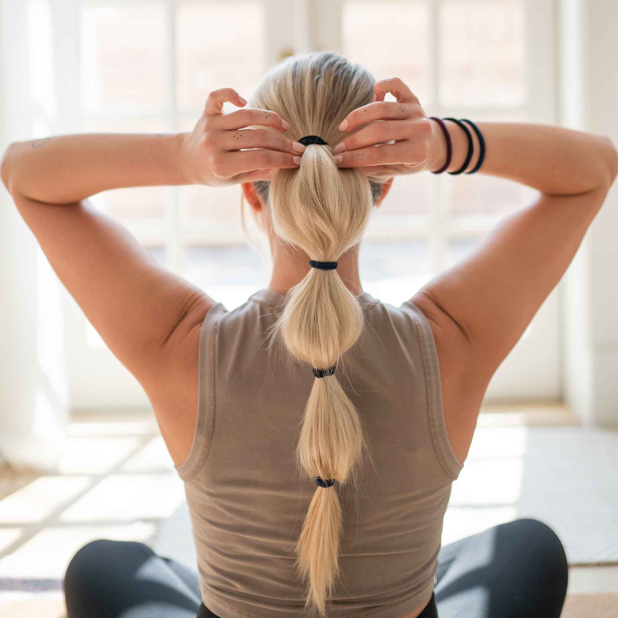 Long blone hair in low pony tail with black hair ties all the way down on a yoga mat