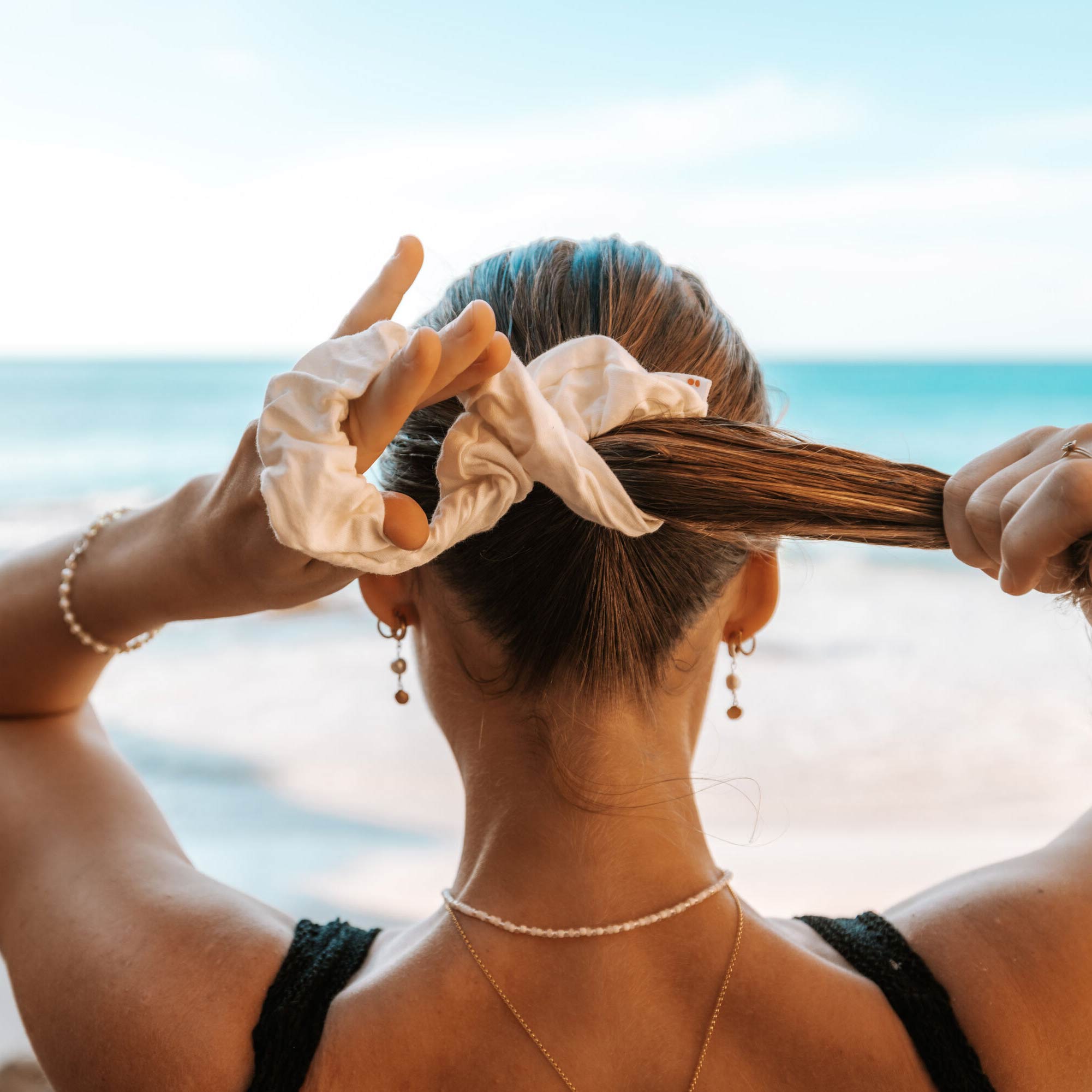 girl at the beach stretching a scrunchie in her hair