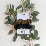 KOOSHOO plastic-free scrunchies in black olive with gum tree branch. Flat lay with beige background #color_black-olive