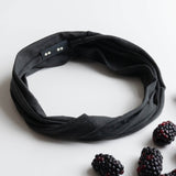 KOOSHOO organic twist headband in raven black off-packaging with fresh black berries scattered around #color_raven-black
