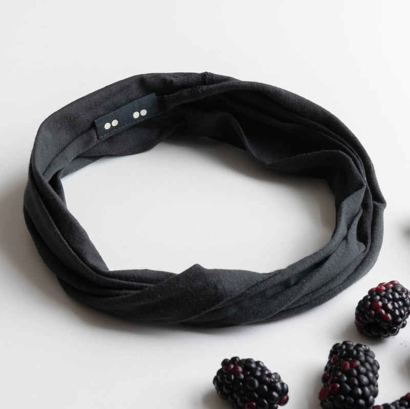 KOOSHOO organic twist headband in raven black off-packaging with fresh black berries scattered around #color_jet-black