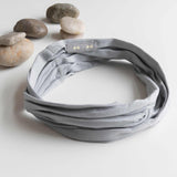 KOOSHOO organic twist headband grounding gray. Flat lay with earthy grey stones #color_grounding-grey