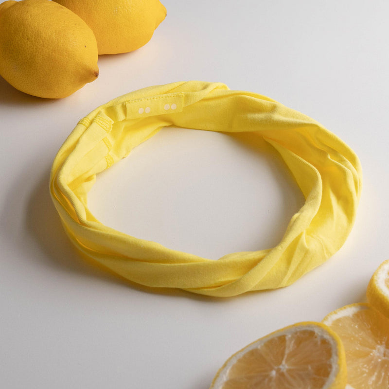 KOOSHOO organic twist headband in illuminating yellow. Off-packaging with lemonade lemons sliced and in a flat lay #color_luminous-yellow